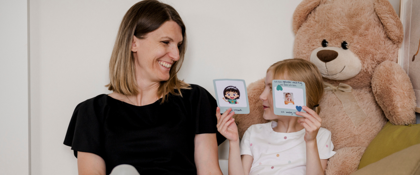Mama und Kind schauen sich Affirmationskarten an