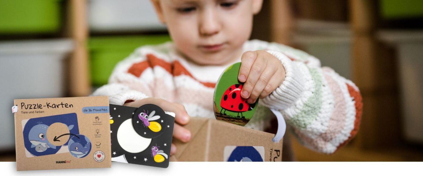 Kind steckt ein Puzzle-Teil in die Öffnung in der Verpackung