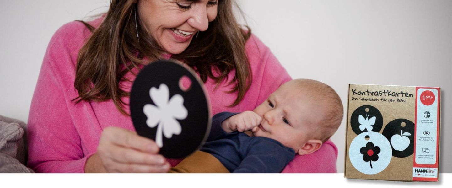 Oma zeigt einem Baby eine Kontrastkarte